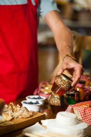 Mid-section of staff checking pickle jar at counter in marketの写真素材