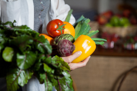 Mid section female costumer holding fresh vegetables and fruits in organic section of supermarketの写真素材