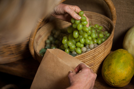 Staff packing grapes in paper bag at supermarketの写真素材