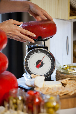 Hands of female staff weighing gouda cheese at counter in supermarketの写真素材