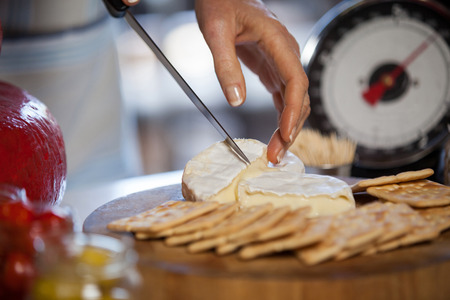 Hand of female staff slicing cheese at counter of supermarketの写真素材