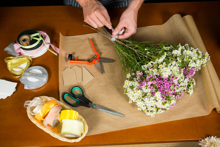 Mid section of male florist preparing a flower bouquet in flower shopの写真素材