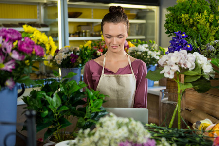 Smiling florist using laptop in flower shopの写真素材