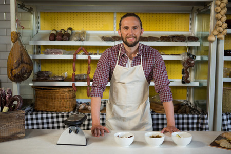 Portrait of smiling male staff standing at meat counter in marketの写真素材