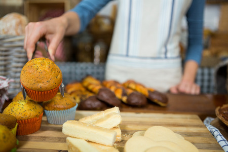 Mid-section of staff working at bakery counter in marketの写真素材