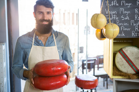 Portrait of staff holding gouda cheese at counter in marketの写真素材