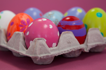 Colorful Easter eggs in egg carton on pink backgroundの写真素材