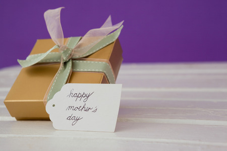 Happy mothers day card with gift box on wooden surfaceの写真素材