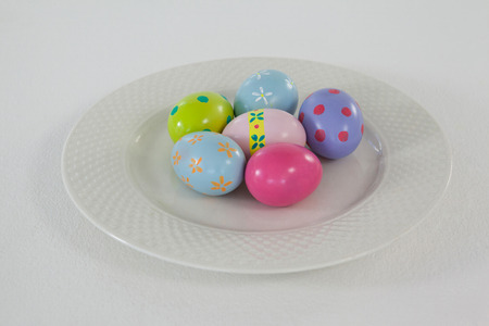 Painted Easter eggs arranged in plate on white backgroundの写真素材