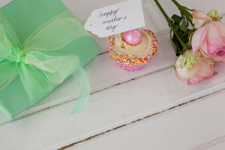 Happy mothers day card with cup cake, gift box and roses on tableの写真素材