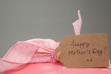 Close-up of gift box with happy mothers day card against grey backgroundの写真素材