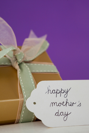 Happy mothers day card with gift box on wooden surfaceの写真素材