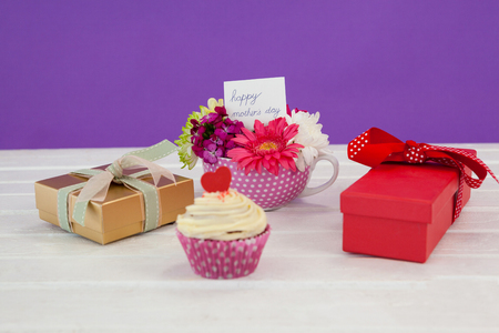 Close-up of cup cake, gift box and fresh flowers on wooden surfaceの写真素材