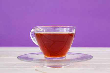 Cup of herbal tea on white table against purple backgroundの写真素材
