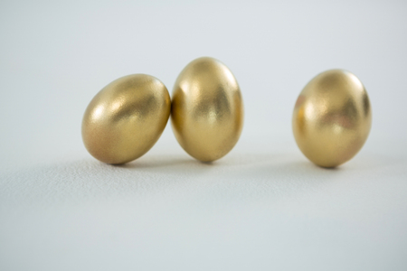 Close-up of golden Easter eggs on white backgroundの写真素材