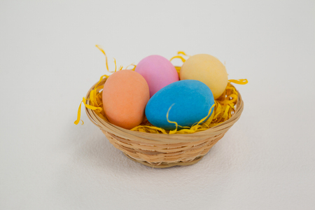 Painted easter eggs in basket against white backgroundの写真素材