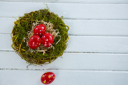 Close-up of red Easter eggs in the nest on wooden surfaceの写真素材