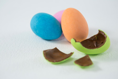 Broken chocolate Easter egg against three chocolate Easter egg on white background