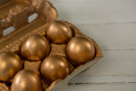 Close-up of golden Easter eggs in the carton on wooden backgroundの写真素材