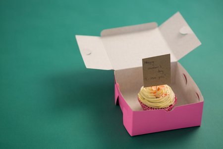 Close-up of cupcake with happy mother day card against green backgroundの写真素材