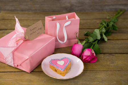 Gift box with roses and heart shape cookies on wooden plankの写真素材