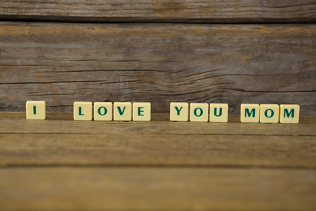 Close-up of I love you mom block on wooden background