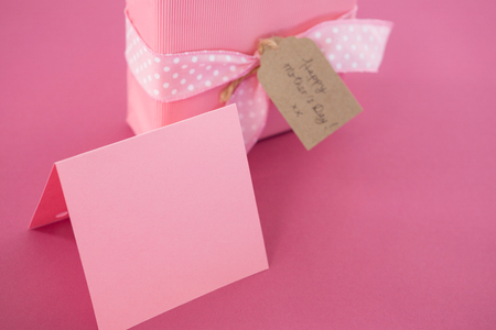 Close-up of gift box with blank card and flower cup against pink backgroundの写真素材