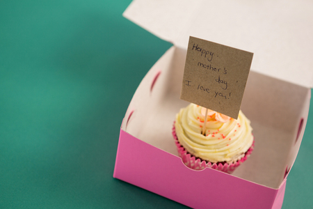 Close-up of cupcake with happy mother day card against green backgroundの写真素材
