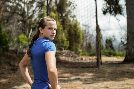 Fit woman standing with her hands on hip in boot camp on a sunny dayの写真素材