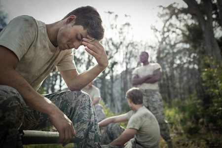 Tired man with hand on head sitting in boot campの写真素材