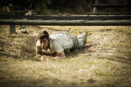 Soldier crawling under the net during obstacle course in boot campの写真素材