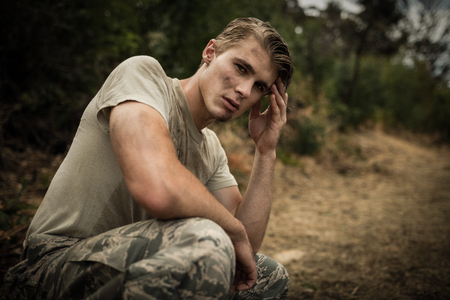 Portrait of soldier with hand on head sitting in boot campの写真素材