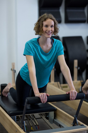 Smiling fit woman exercising on reformer in gymの写真素材