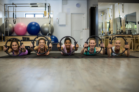 Group of fit women exercising with pilates ring in gymの写真素材