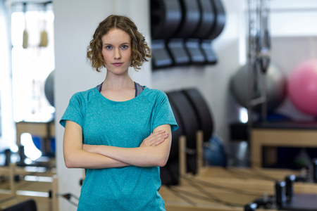 Portrait of fit woman standing with arms crossed in gymの写真素材