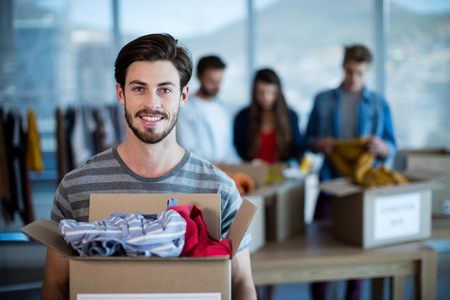 Portrait of smiling man holding a donation box in officeの写真素材