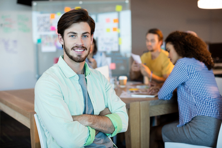 Portrait of smiling man with arms crossed in officeの写真素材