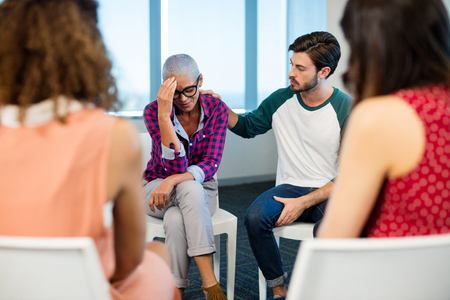 Creative business team consoling upset colleague at officeの写真素材