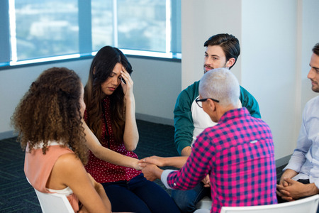 Creative business team consoling upset colleague at officeの写真素材