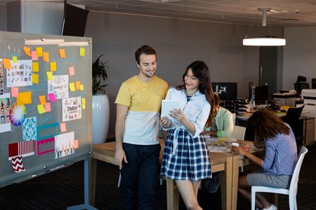 Creative business people looking at digital tablet at officeの写真素材