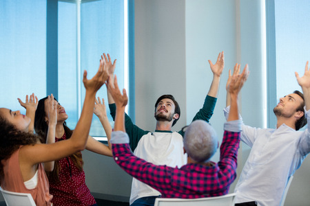 Creative business team sitting with their arms up at officeの写真素材