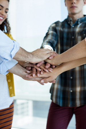 Creative business team stacking hands together in office