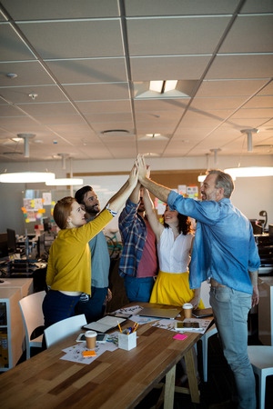 Creative business team giving a high five to each other in officeの写真素材