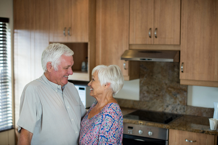 Happy senior couple looking at each other in kitchen at home
