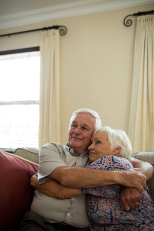 Happy senior couple embracing each other in living room at homeの写真素材