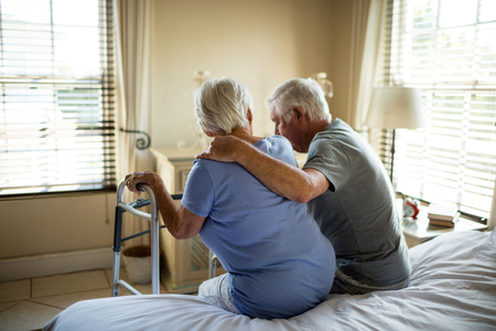 Senior man consoling woman in bedroom at homeの写真素材