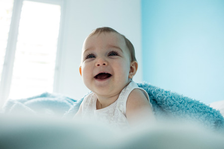 Cute baby girl smiling on bed in bedroomの写真素材
