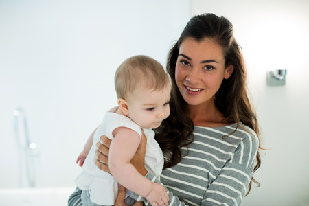 Mother holding her baby girl at home