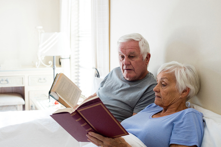 Senior couple reading books in the bedroom at homeの写真素材