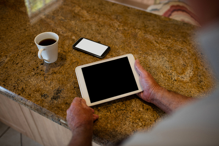 Senior man holding digital tablet in the kitchen at homeの写真素材